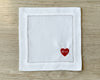 White napkin with a red heart and initials 'M+L' on a wooden surface