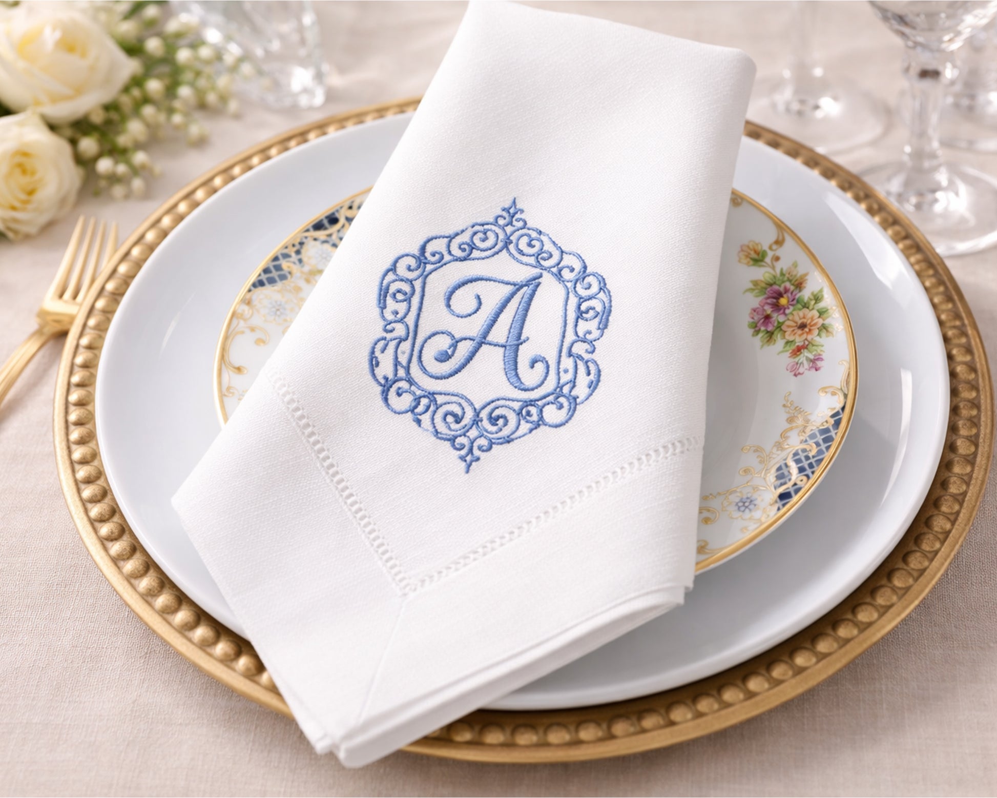 White napkin with blue monogram 'A' on a decorative plate with gold rim