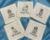 A crisp white cotton hemstitch napkin featuring a detailed black embroidered Doodle dog sitting next to a martini glass icon.