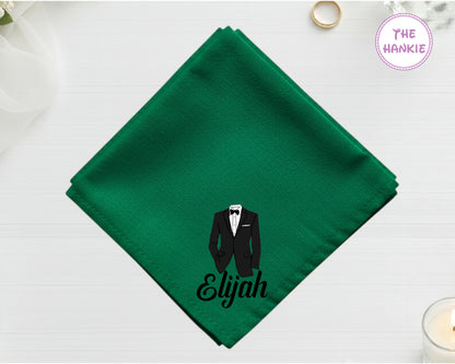 A lush forest green cotton pocket square featuring the name "Elijah" below a detailed black and white vinyl print of a formal tuxedo suit.