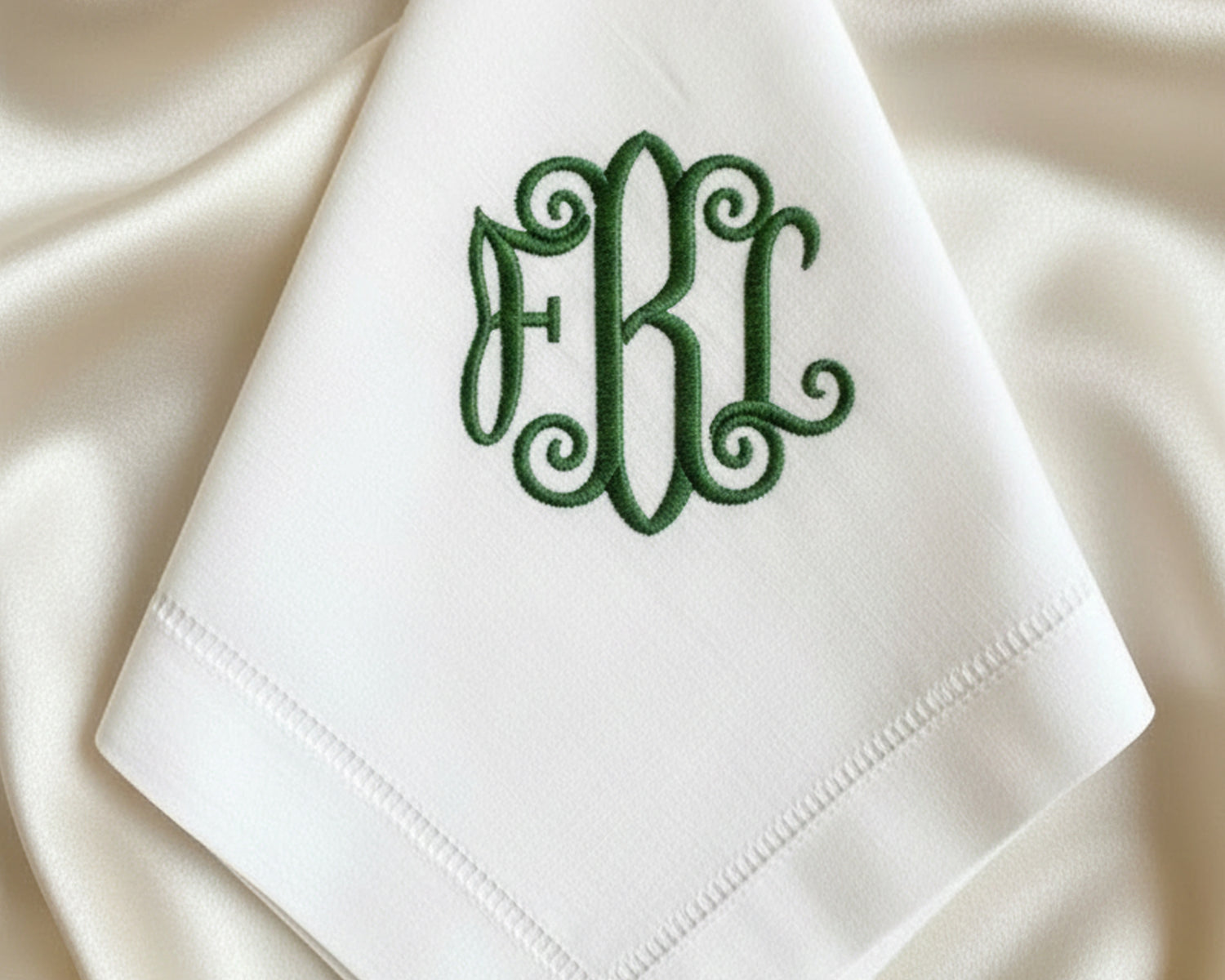 Close-up of high-quality sage green embroidery showing the intricate bow design and classic hemstitch border