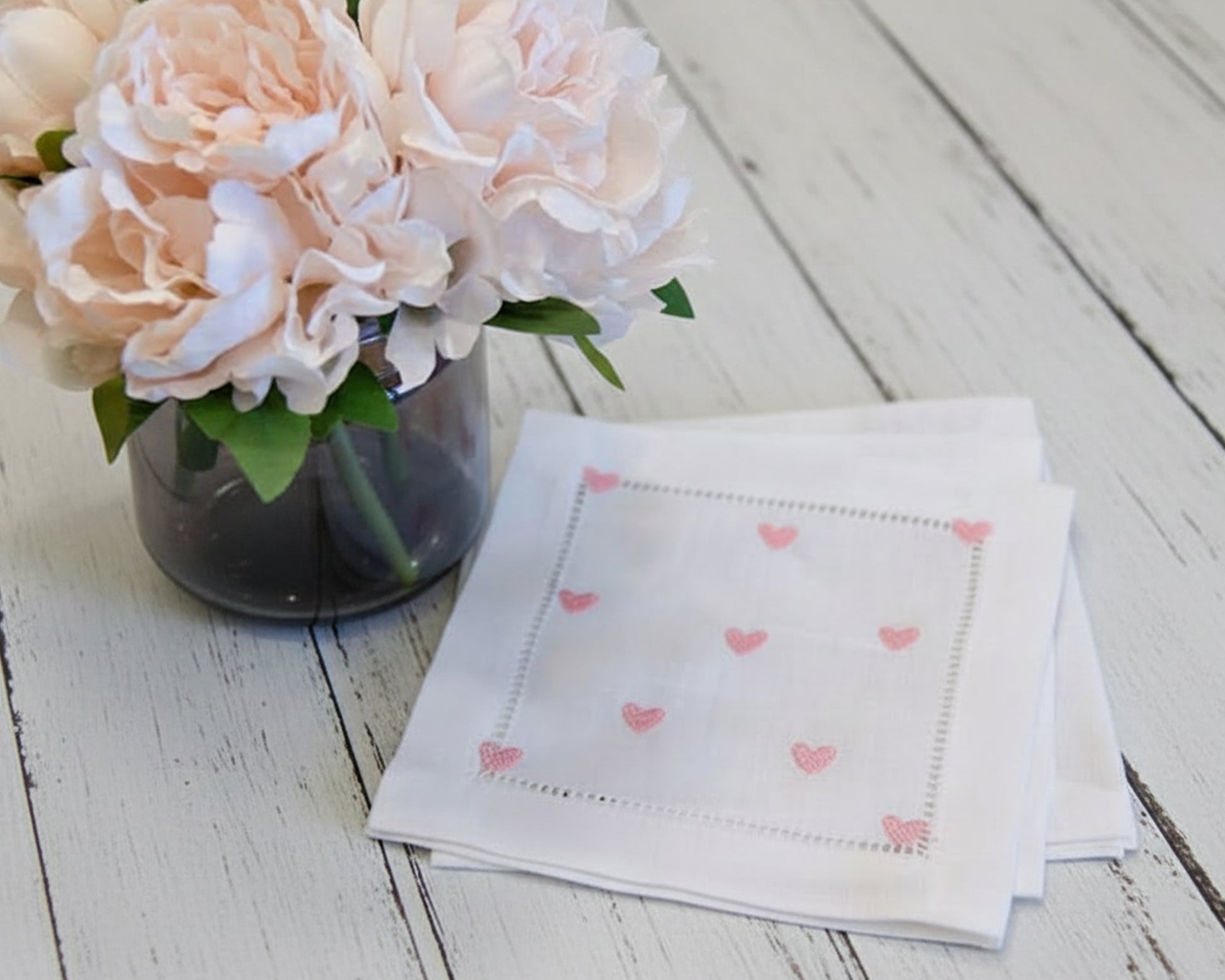 White cotton hankie with pink heart embroidery styled with flowers on a rustic table