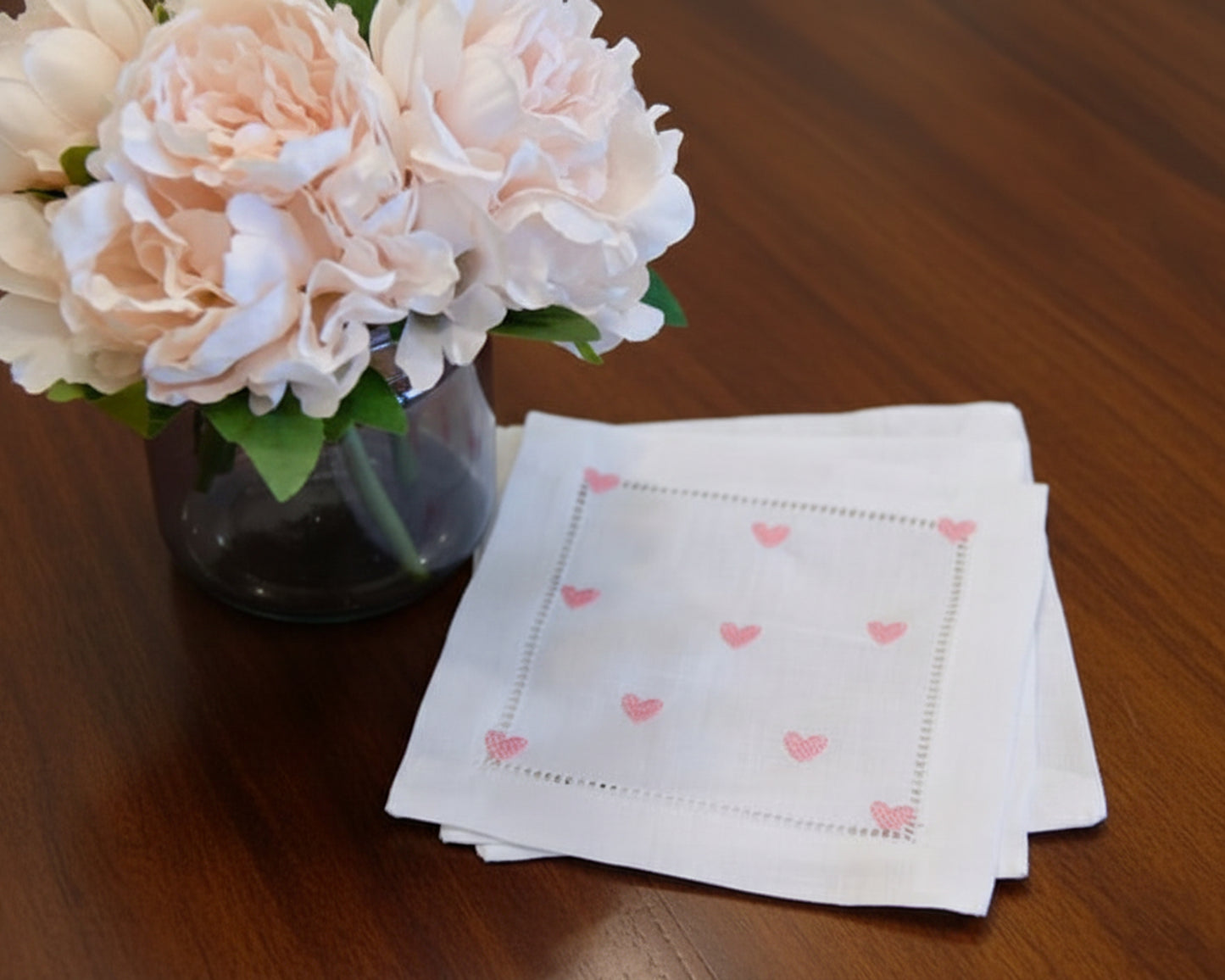 Stack of embroidered heart cotton hankies arranged on a wooden table