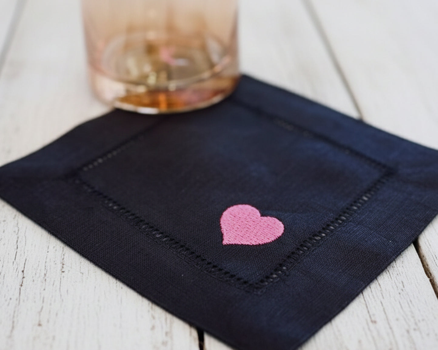Navy blue napkin with a pink heart design on a wooden surface