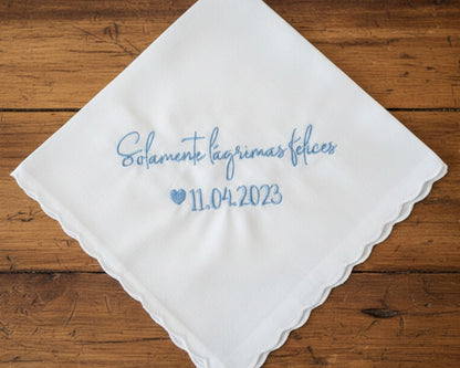 A customized 100% cotton handkerchief featuring the Spanish sentiment for happy tears and a wedding date, placed on a rustic dark wood surface.