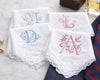 Set of embroidered handkerchiefs with initials on a marble surface.