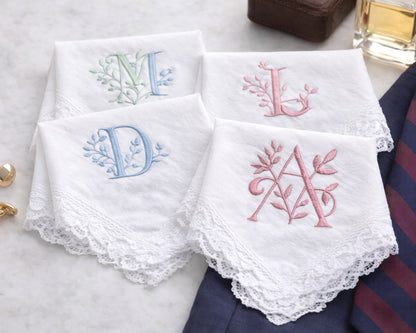 Set of embroidered handkerchiefs with initials on a marble surface.