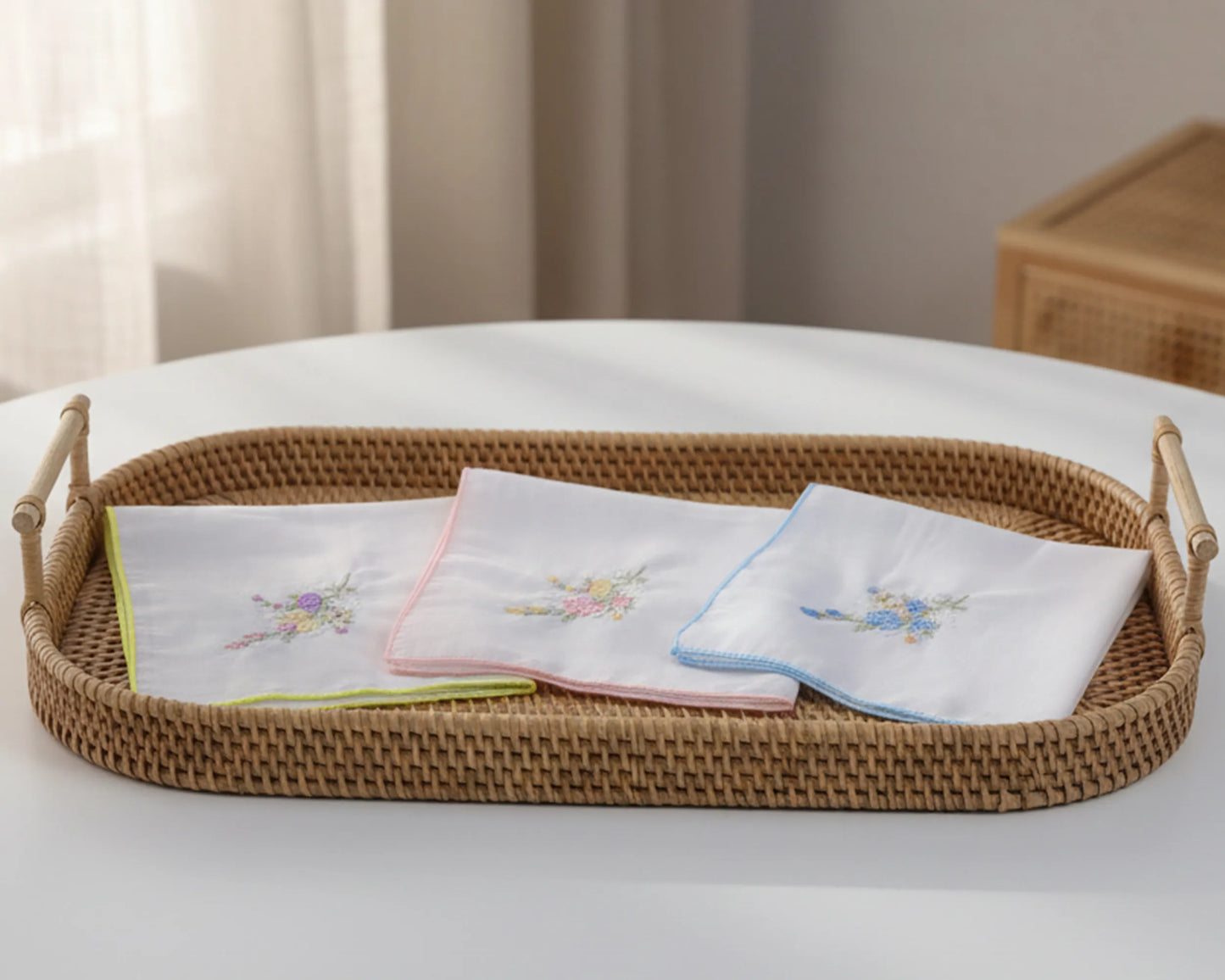 Wicker tray with embroidered handkerchiefs on a white surface