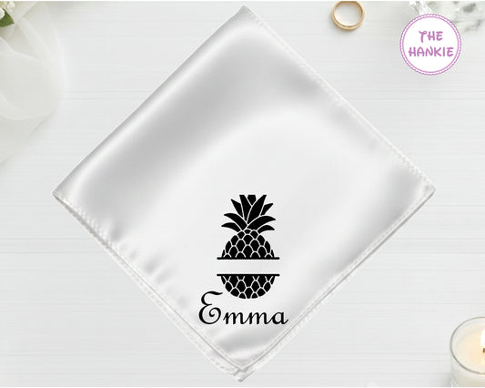 A shimmering pearl white luxury satin handkerchief personalized with the name "Emma" inside a black split-monogram pineapple embroidery.
