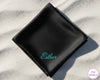 A premium black satin pocket square with the name "Esther" personalized in a shimmering teal script embroidery.