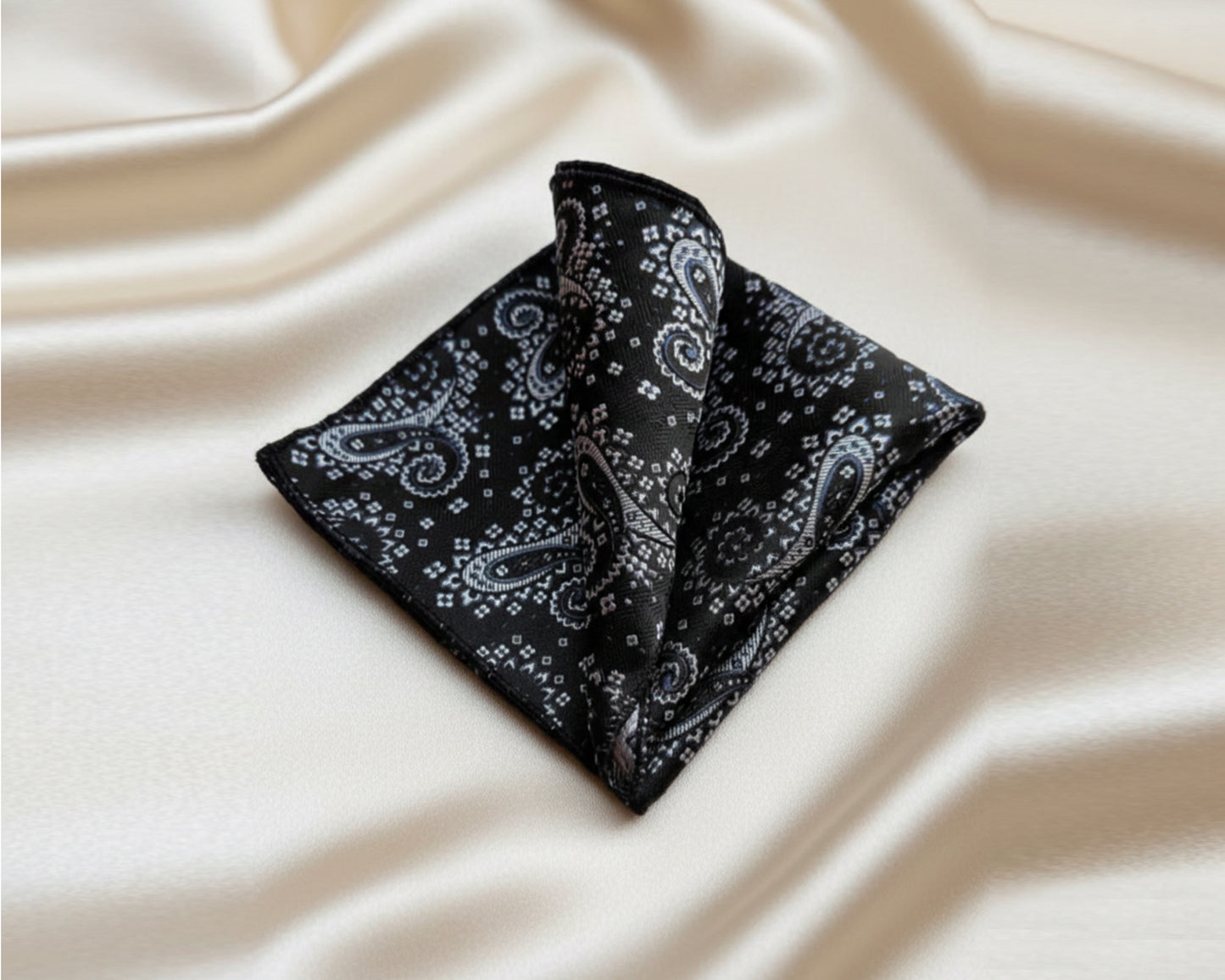 A luxury black and slate paisley cotton handkerchief styled in a sharp three point fold for a formal suit jacket.