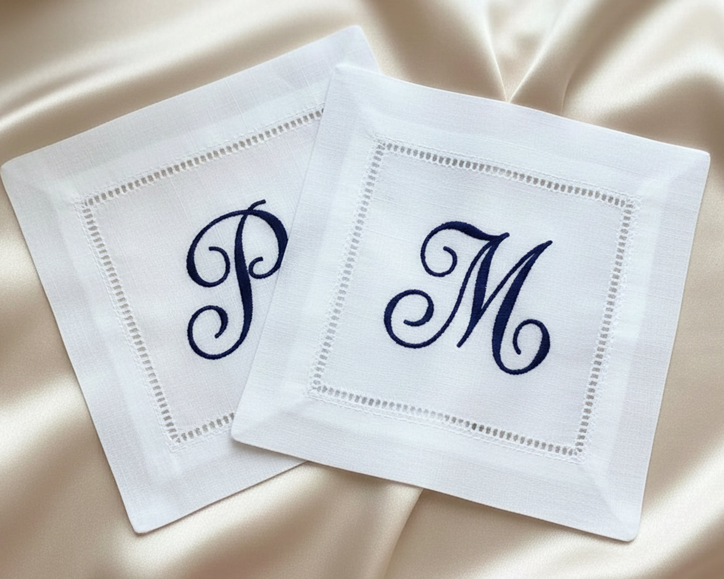 White cotton dinner napkin featuring festive green holly leaves and red berry embroidery with a traditional hemstitch border