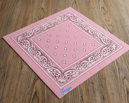 An angled view of a soft pink paisley handkerchief featuring "Freya" embroidered in a blue chain stitch font.