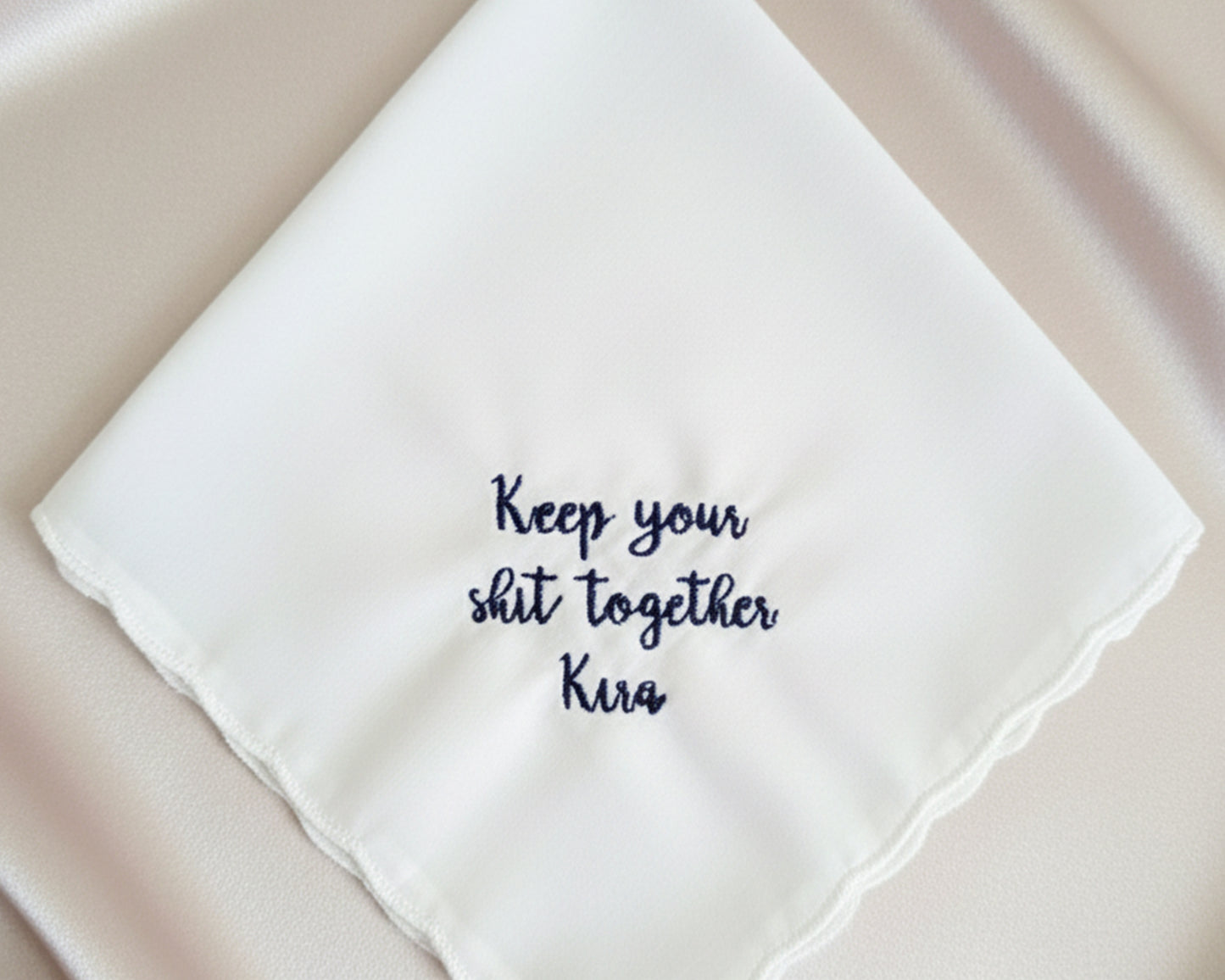 A personalized wedding handkerchief with a navy blue embroidered message saying "Keep your shit together Kira."