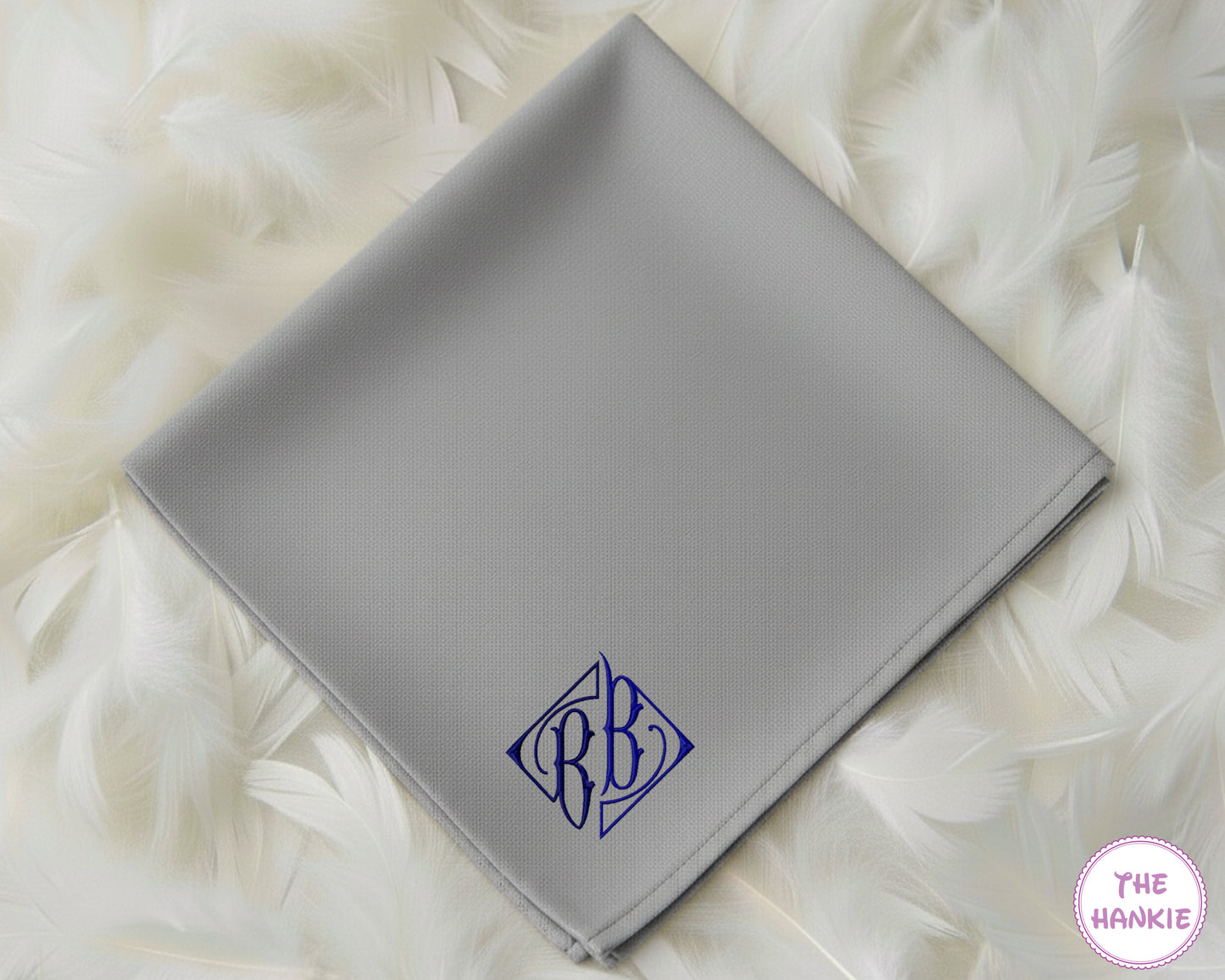 A modern grey cotton handkerchief featuring a personalized dark blue diamond-style crest monogram with the initials "BB".
