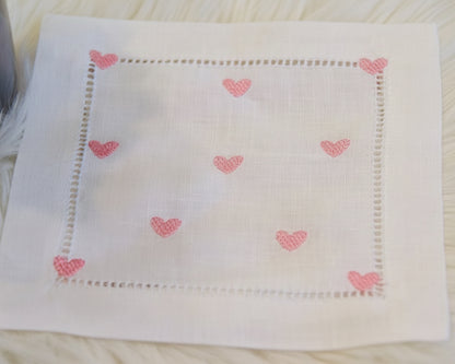 Close‑up of white cotton handkerchief featuring delicate pink heart embroidery

