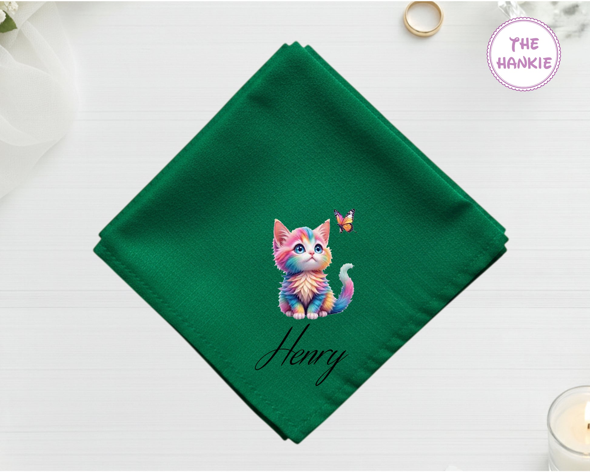 A lush forest green luxury satin handkerchief featuring the name "Henry" and a whimsical, pastel-colored rainbow kitten looking up at a butterfly.