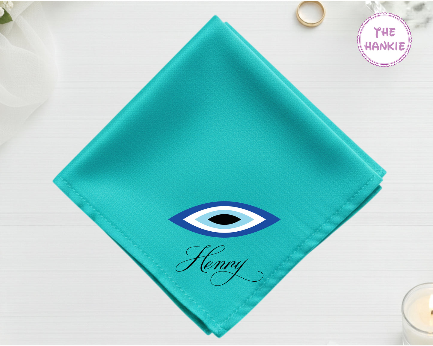 A radiant turquoise cotton handkerchief customized with "Henry" below a minimalist blue, black, and white circular Nazar evil eye design.