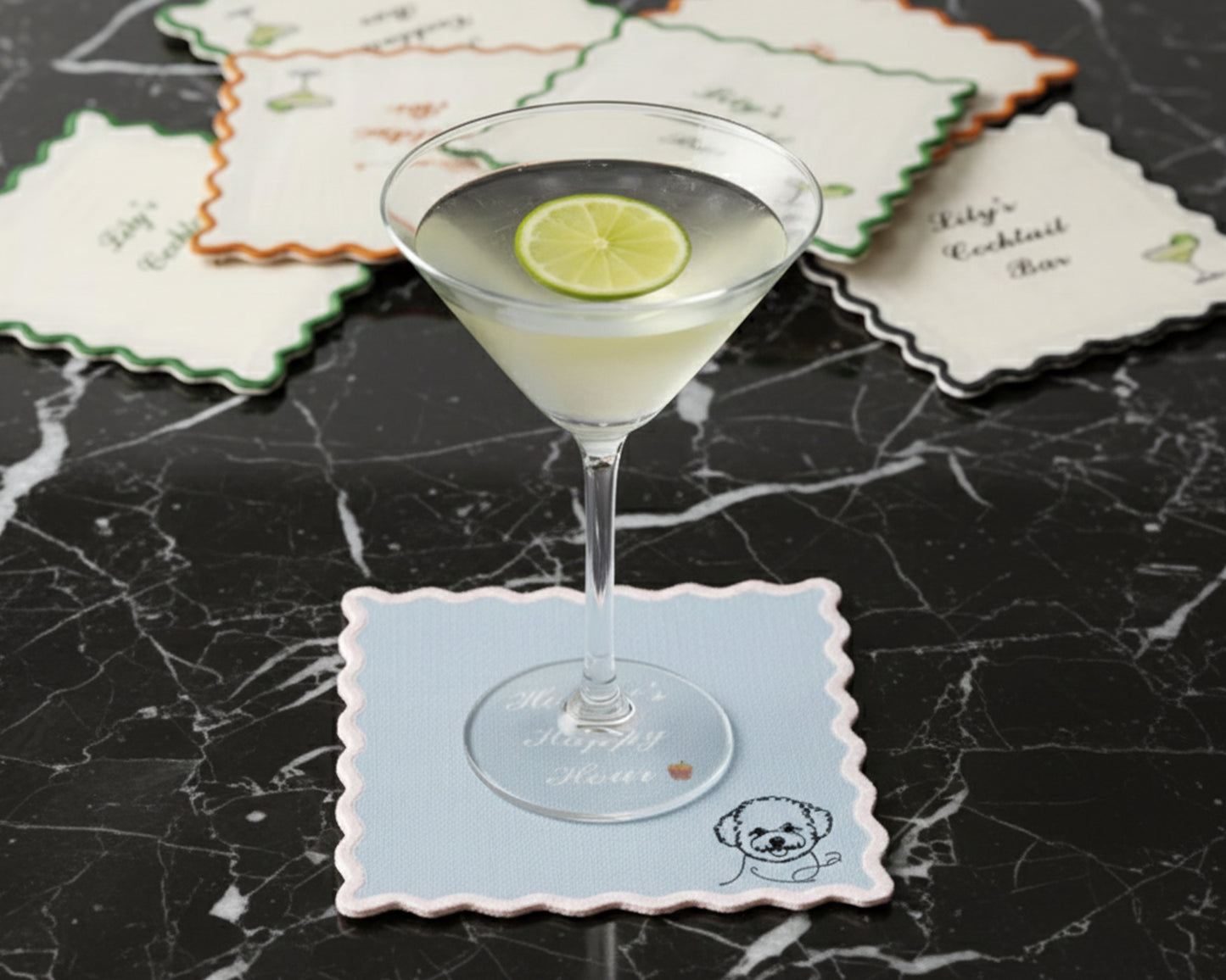A light blue scalloped-edge bar napkin under a martini glass, personalized with "Honey’s Happy Hour" and a minimalist poodle icon.