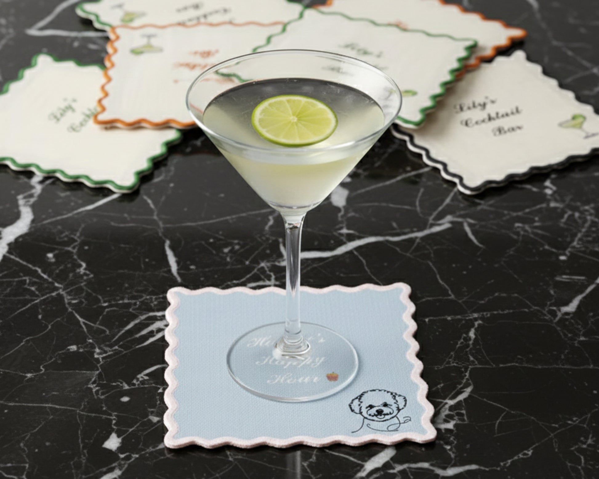 A light blue scalloped-edge bar napkin under a martini glass, personalized with "Honey’s Happy Hour" and a minimalist poodle icon.