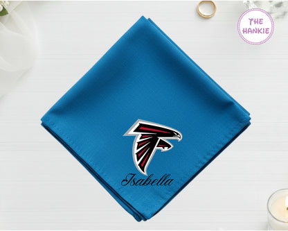 A brilliant sapphire blue cotton pocket square featuring the name "Isabella" below a red, black, and silver Atlanta Falcons NFL team icon.