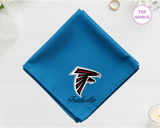 A brilliant sapphire blue cotton pocket square featuring the name "Isabella" below a red, black, and silver Atlanta Falcons NFL team icon.