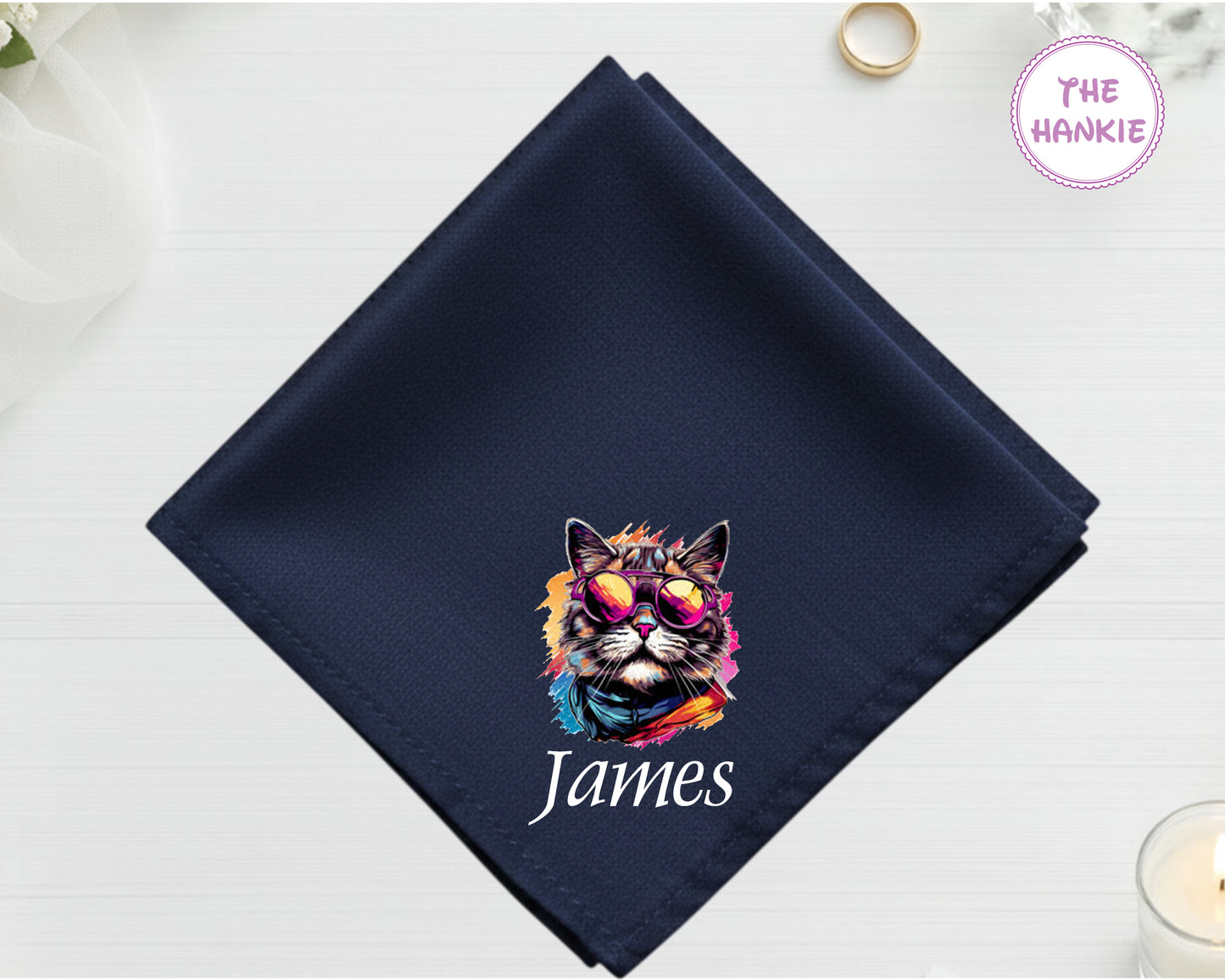 A midnight navy luxury satin handkerchief personalized with the name "James" below a vibrant, multi-colored artistic cat portrait wearing sunglasses.