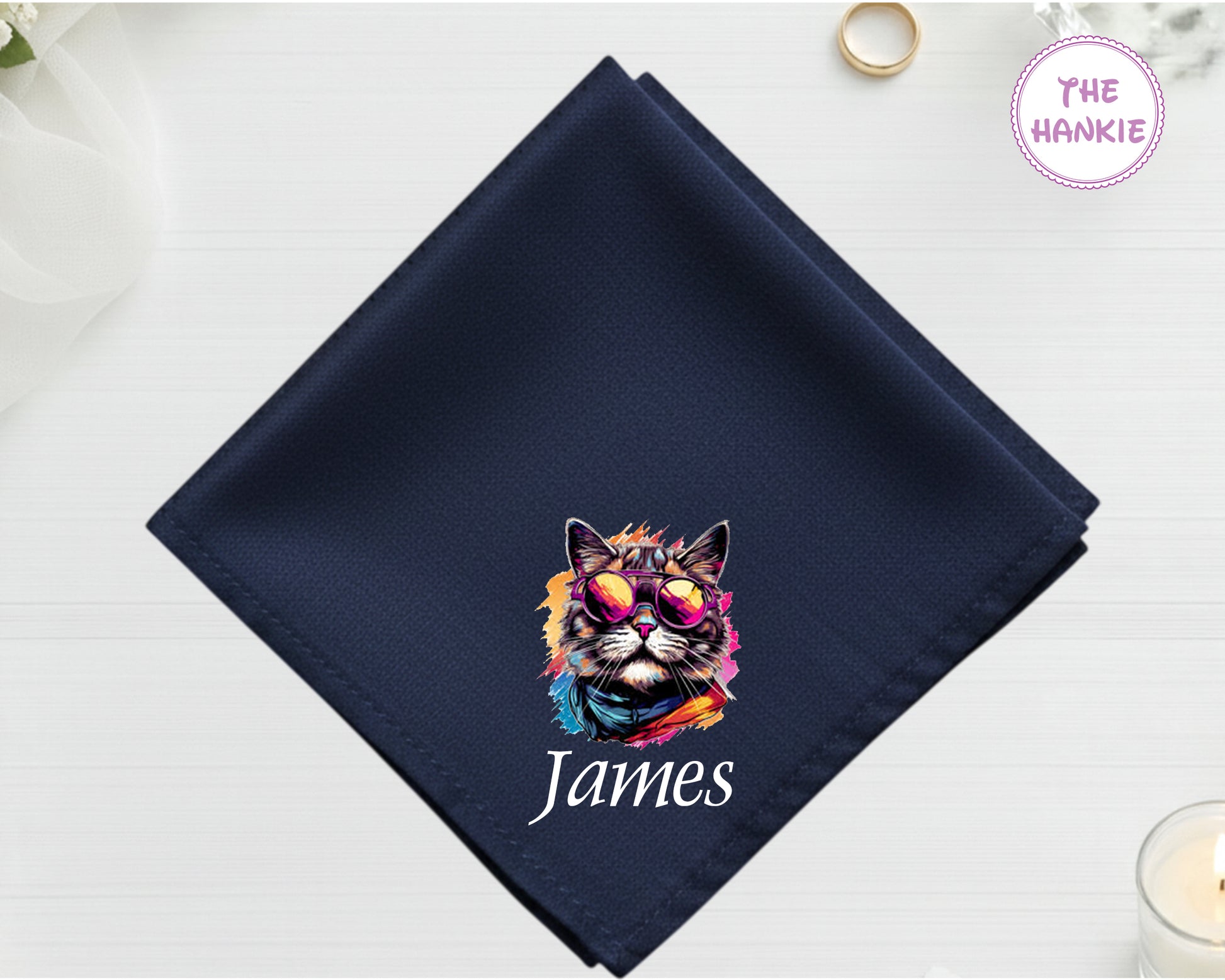 A midnight navy luxury satin handkerchief personalized with the name "James" below a vibrant, multi-colored artistic cat portrait wearing sunglasses.