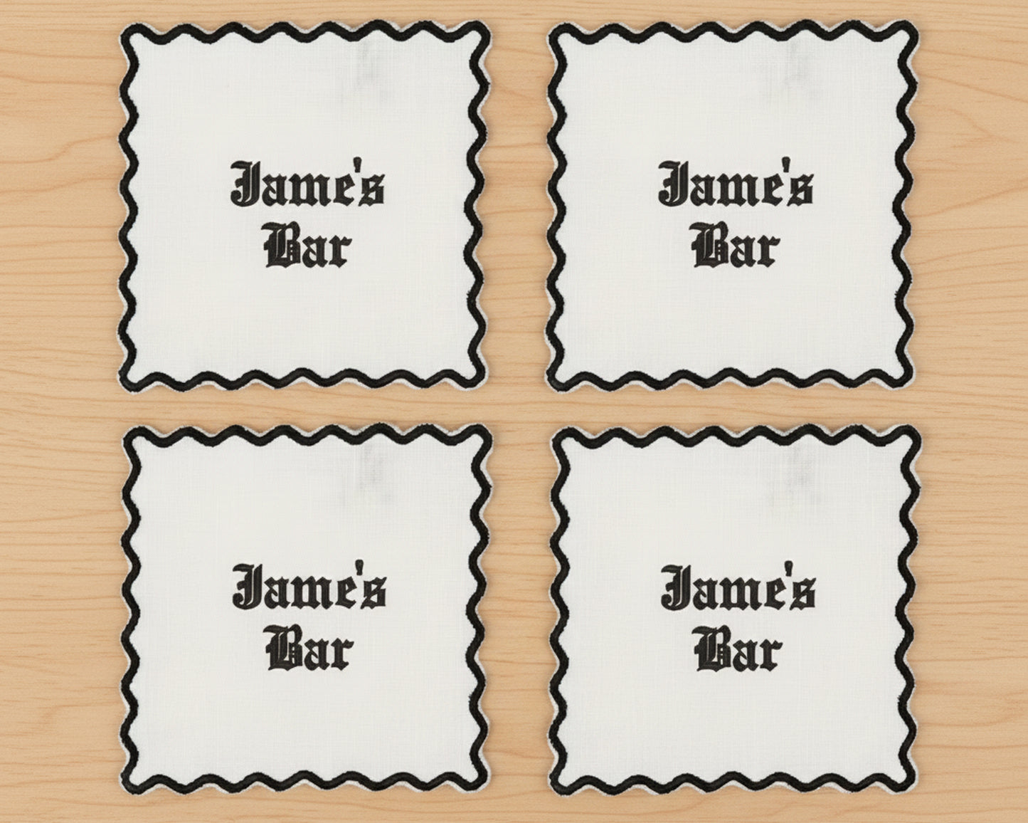 Four olive green linen cocktail napkins with blue scalloped borders and a custom "KRB" vinyl monogram in the corner.