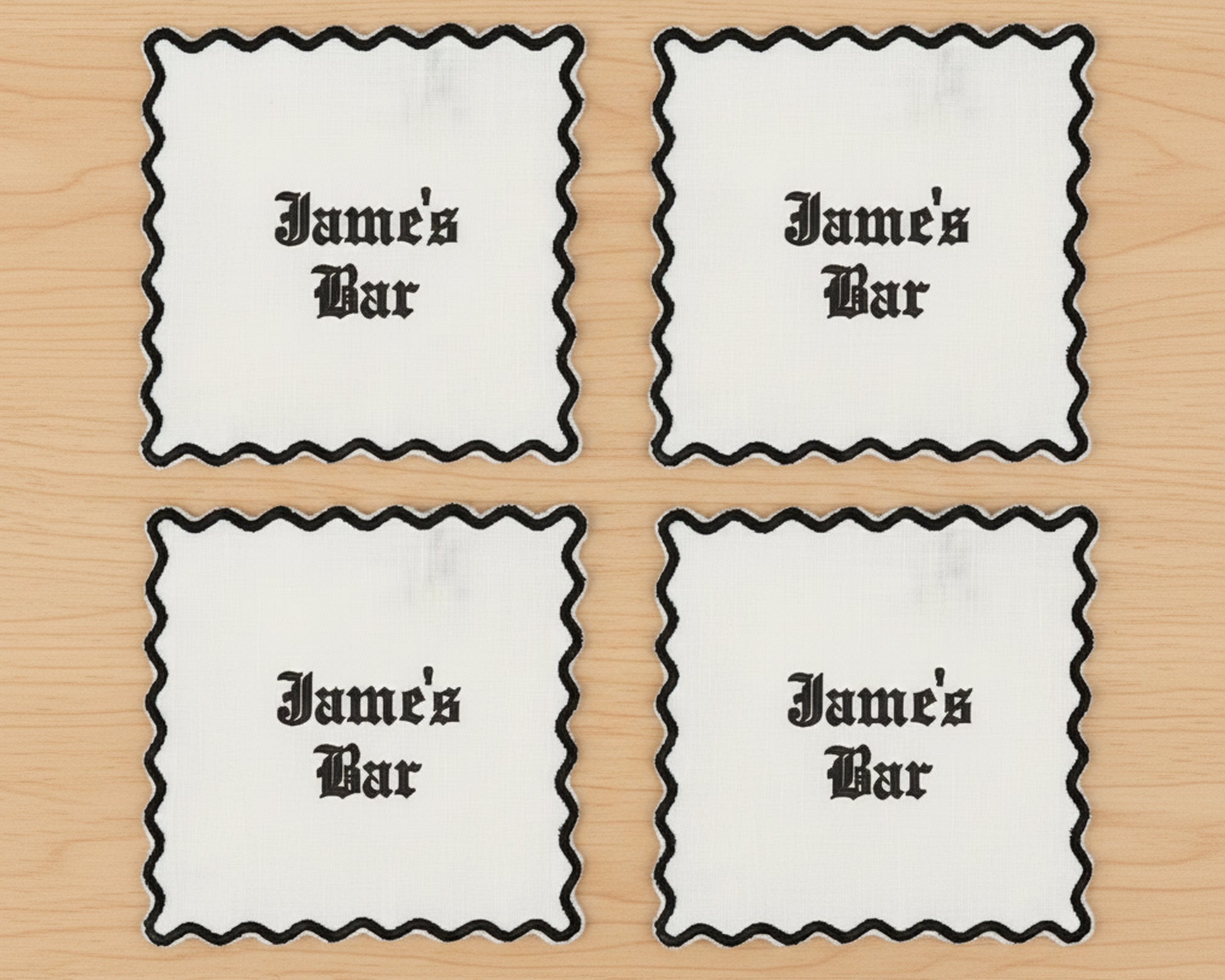 Four olive green linen cocktail napkins with blue scalloped borders and a custom "KRB" vinyl monogram in the corner.