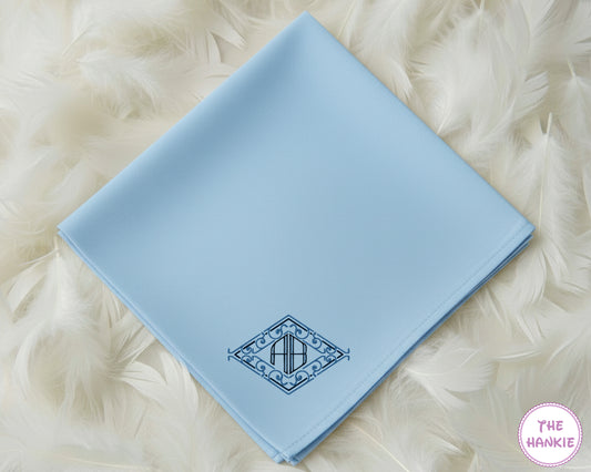 A light blue premium cotton handkerchief featuring a custom dark blue diamond crest monogram with the initials "AB".