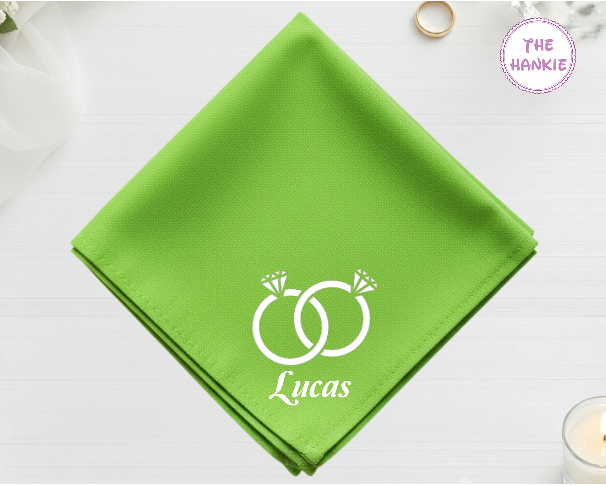 A fresh spring green cotton handkerchief featuring the name "Lucas" and white embroidery depicting two sparkling diamond rings entwined.