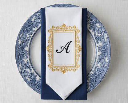 Bespoke white napkin with a detailed green heraldic crest featuring a lion, mountain motif, and 'R' initial
