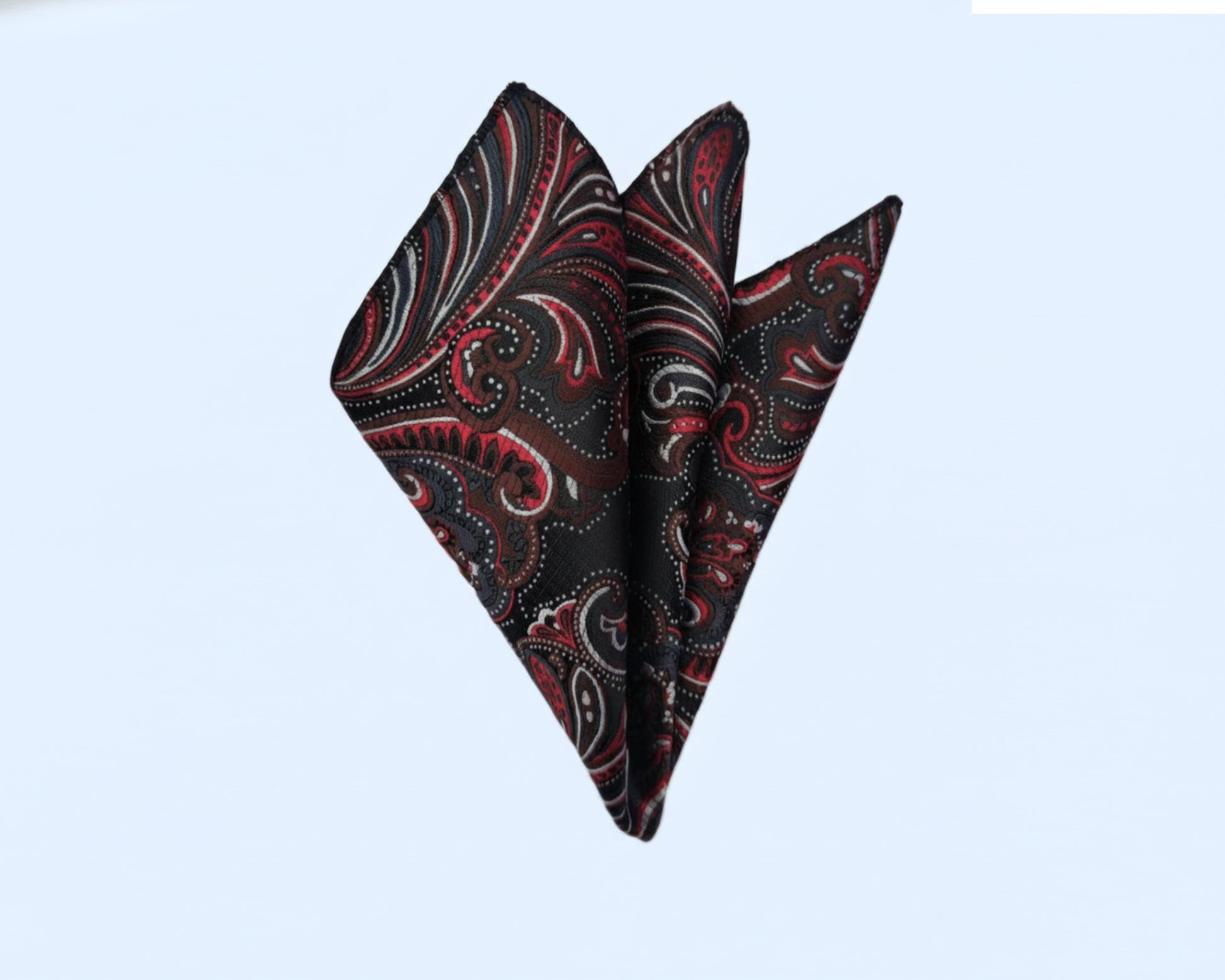 A luxury red and black paisley silk pocket square styled in a sharp three-point fold for a formal suit.