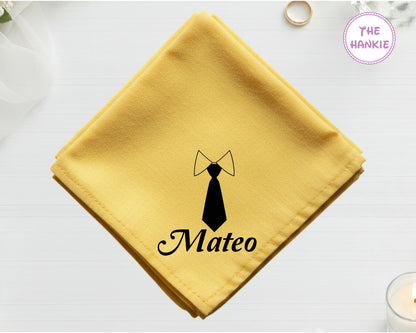 A golden harvest yellow cotton handkerchief customized with "Mateo" below a minimalist black vinyl print of a necktie and collar.