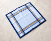 Folded fabric with blue and gold plaid pattern on a beige surface