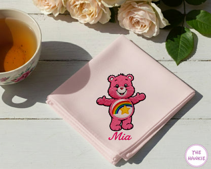 A soft sky pink cotton handkerchief personalized with the name "mia" and an embroidered pinkBedtime Bear character