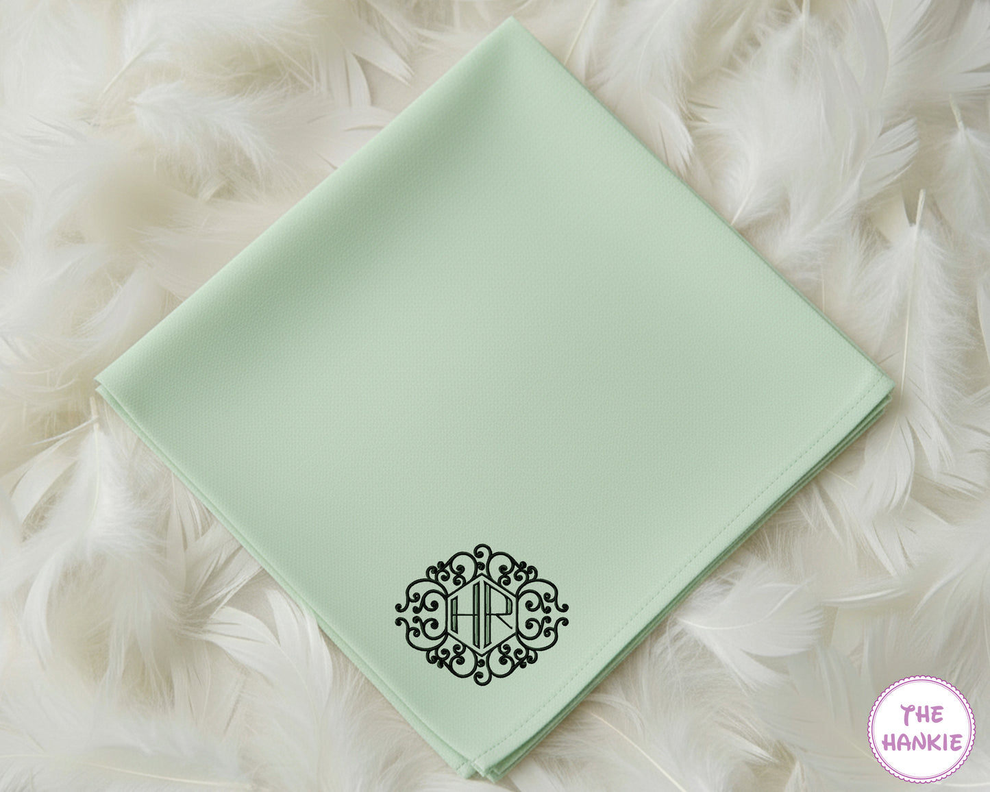 A mint green 100% cotton handkerchief showcasing a bold, black circular crest monogram with the initials "HRC".