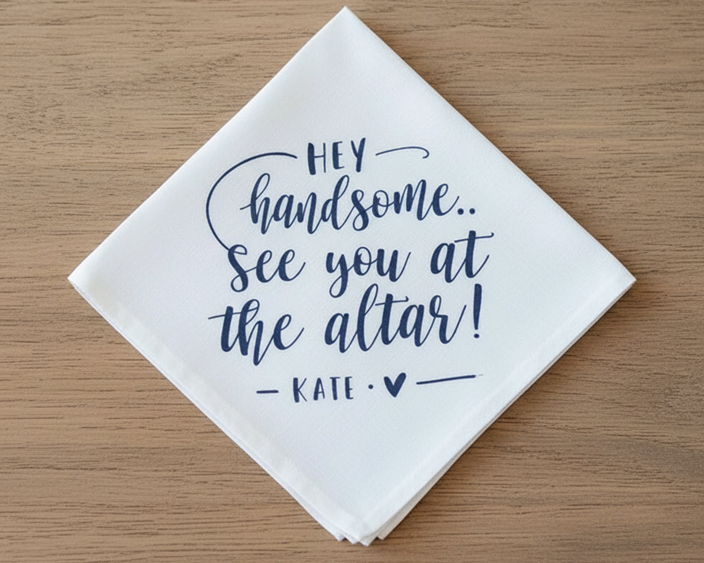 A white cotton handkerchief with decorative navy blue vinyl script reading "HEY handsome... See you at the altar! — KATE — ❤".