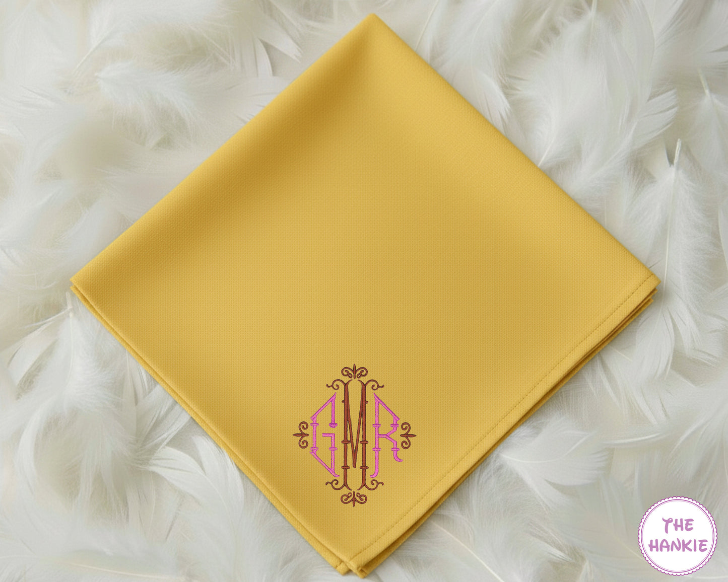 A vibrant mustard yellow 100% cotton handkerchief featuring an intricate, decorative three-initial "GMR" monogram in pink and brown embroidery.