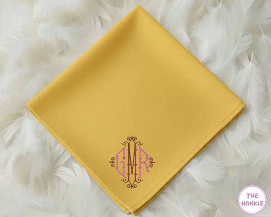 A vibrant mustard yellow 100% cotton handkerchief featuring an intricate, decorative three-initial "GMR" monogram in pink and brown embroidery.