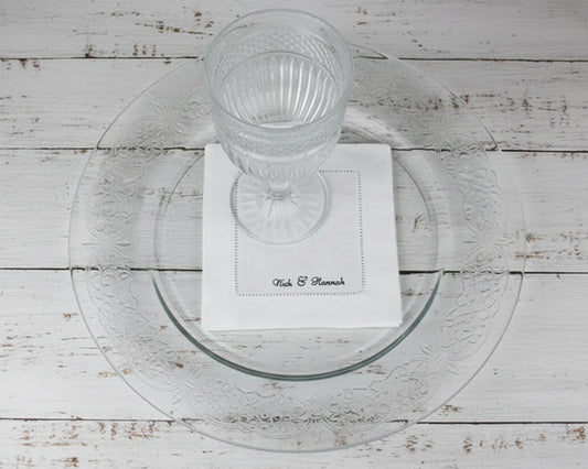 A premium white 100% linen hemstitch napkin featuring "Nick & Hannah" personalized script embroidery under a clear water glass.
