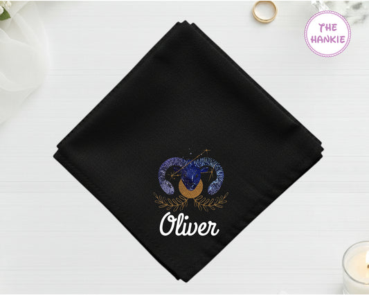 A midnight black cotton handkerchief personalized with the name "Oliver" below an indigo and gold Aries ram star sign icon.