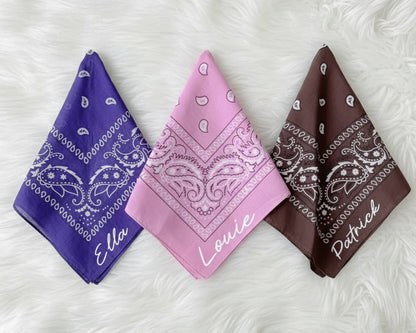A stack of four embroidered bandanas in burgundy, cream, black, and blue with custom names