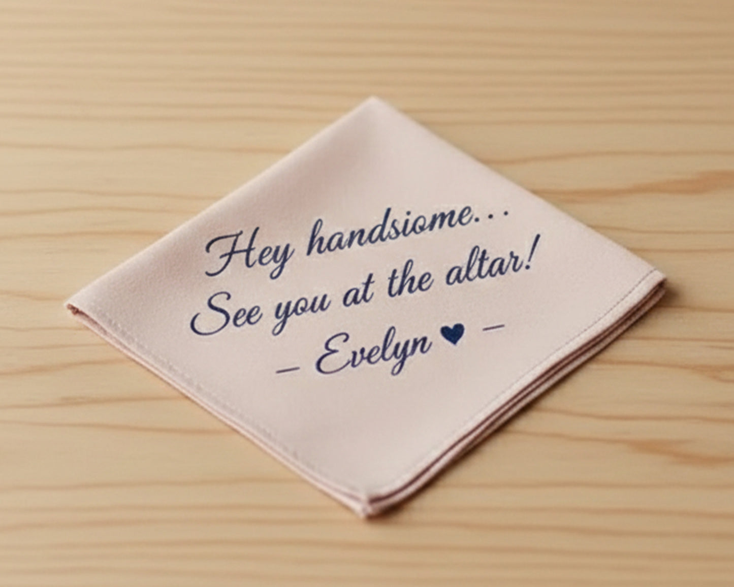 A soft blush pink cotton handkerchief featuring a custom navy vinyl print: "Hey handsome... See you at the altar! — Evelyn ❤ —".