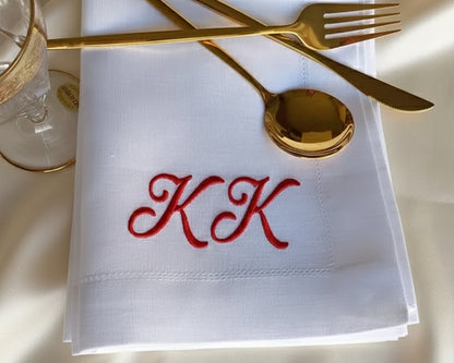 Crisp white cotton guest towel with a navy blue monogram and a traditional hemstitched border hanging in a luxury bathroom