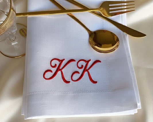 Crisp white cotton guest towel with a navy blue monogram and a traditional hemstitched border hanging in a luxury bathroom