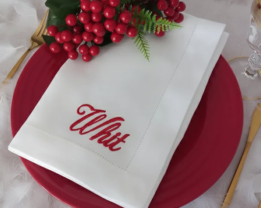 White napkin with red text on a red plate with berries and greenery