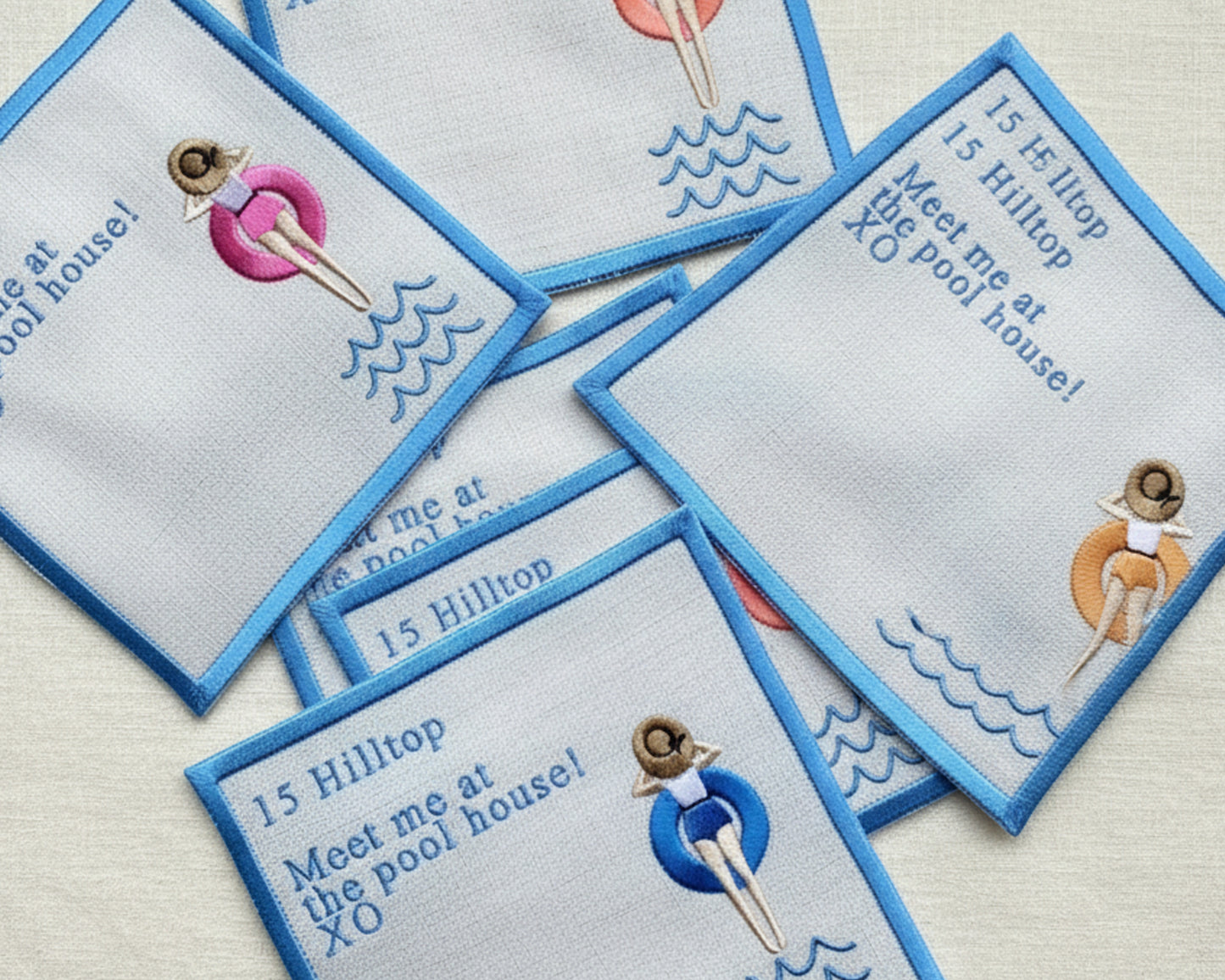 Close-up of white beverage napkins personalized with a "15 Hilltop" address and a "Meet me at the pool house" message.