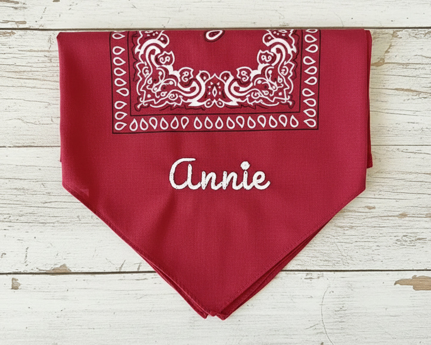 Four folded bandanas in red, cream, black, and light blue showcasing different custom name embroidery styles